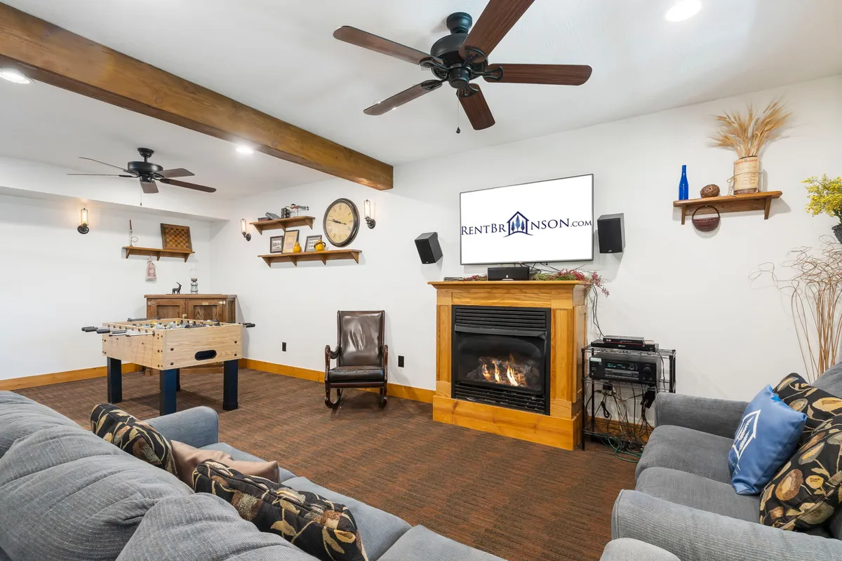 A bright, welcoming lounge area featuring a plush sofa, a foosball table, a stone fireplace, and a large television. The mix of gaming and relaxing areas makes the space ideal for both friendly competitions and family movie nights, capturing the playful yet cozy ambience of the recreation lounge.