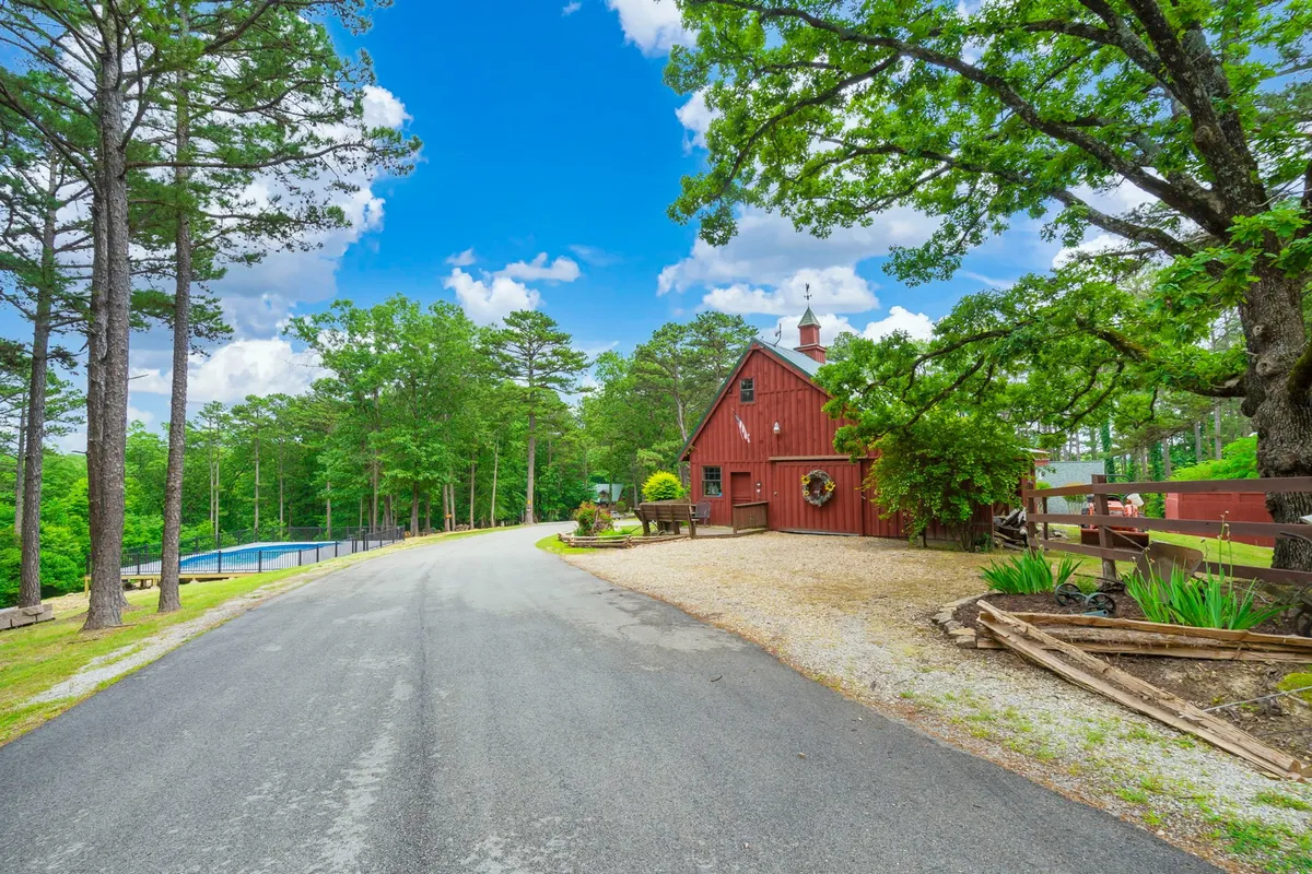 A captivating view featuring a red barn, expansive tree-shaded grounds, and a sparkling pool. The scene is peaceful and inviting, suggesting ample space for outdoor team-building, casual gatherings, or exploring nature.