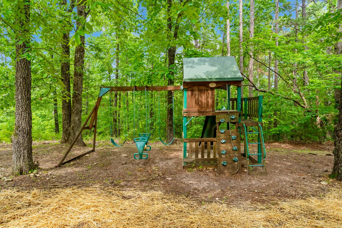 The image features a vibrant outdoor playset equipped with a swing and climbing wall, set against a backdrop of lush greenery. The scene radiates joy and adventure, showing where children and families can enjoy memorable outdoor playtime.